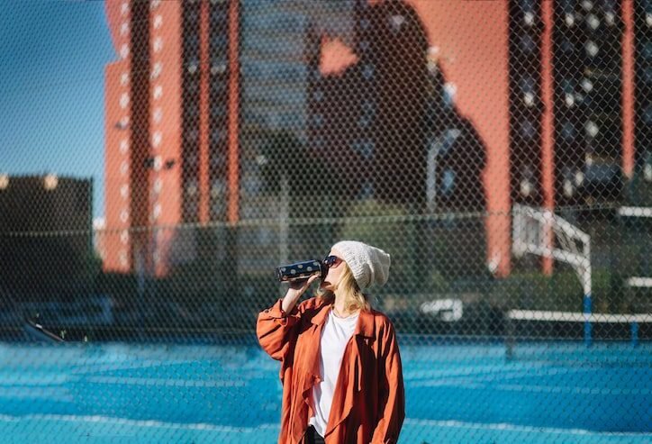 Candid street photography of a woman enjoying a drink on a city street